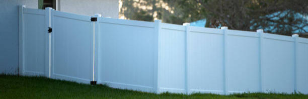 Slated fence with wood panels on the ground.