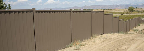 A dark grey fence with white posts next to a pale teal gate.